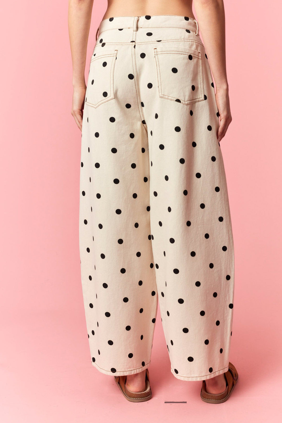 Polka dot pants worn by a person on a pink background