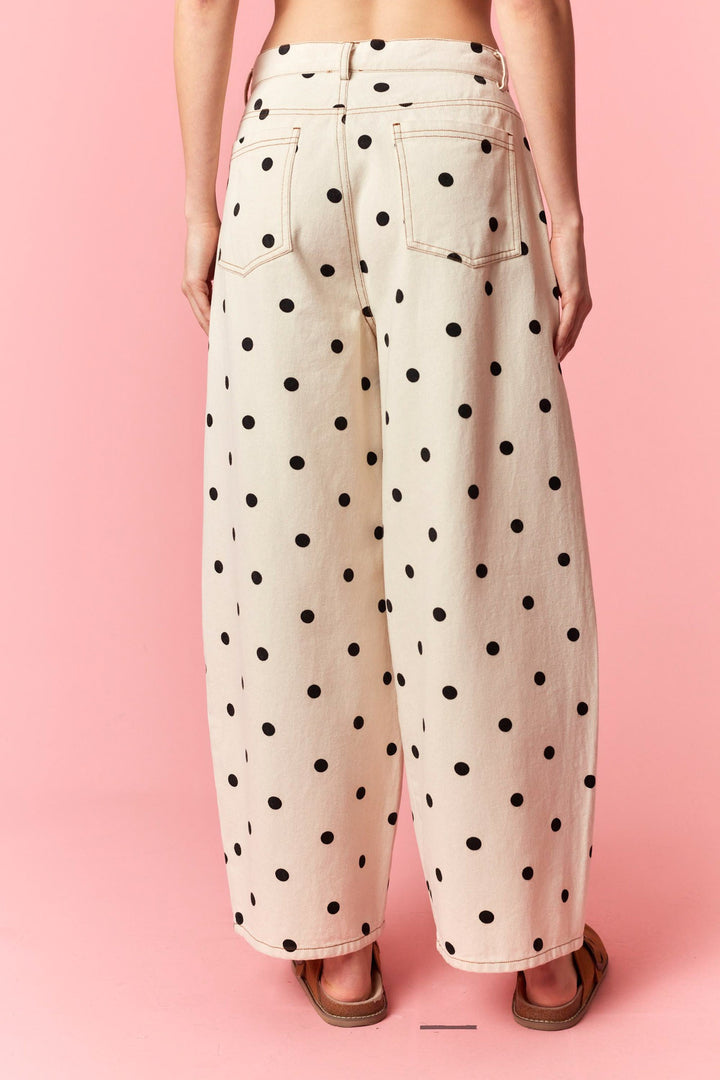 Polka dot pants worn by a person on a pink background