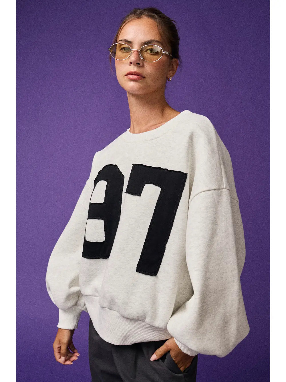 Person wearing a white sweater with black numbers on a purple background