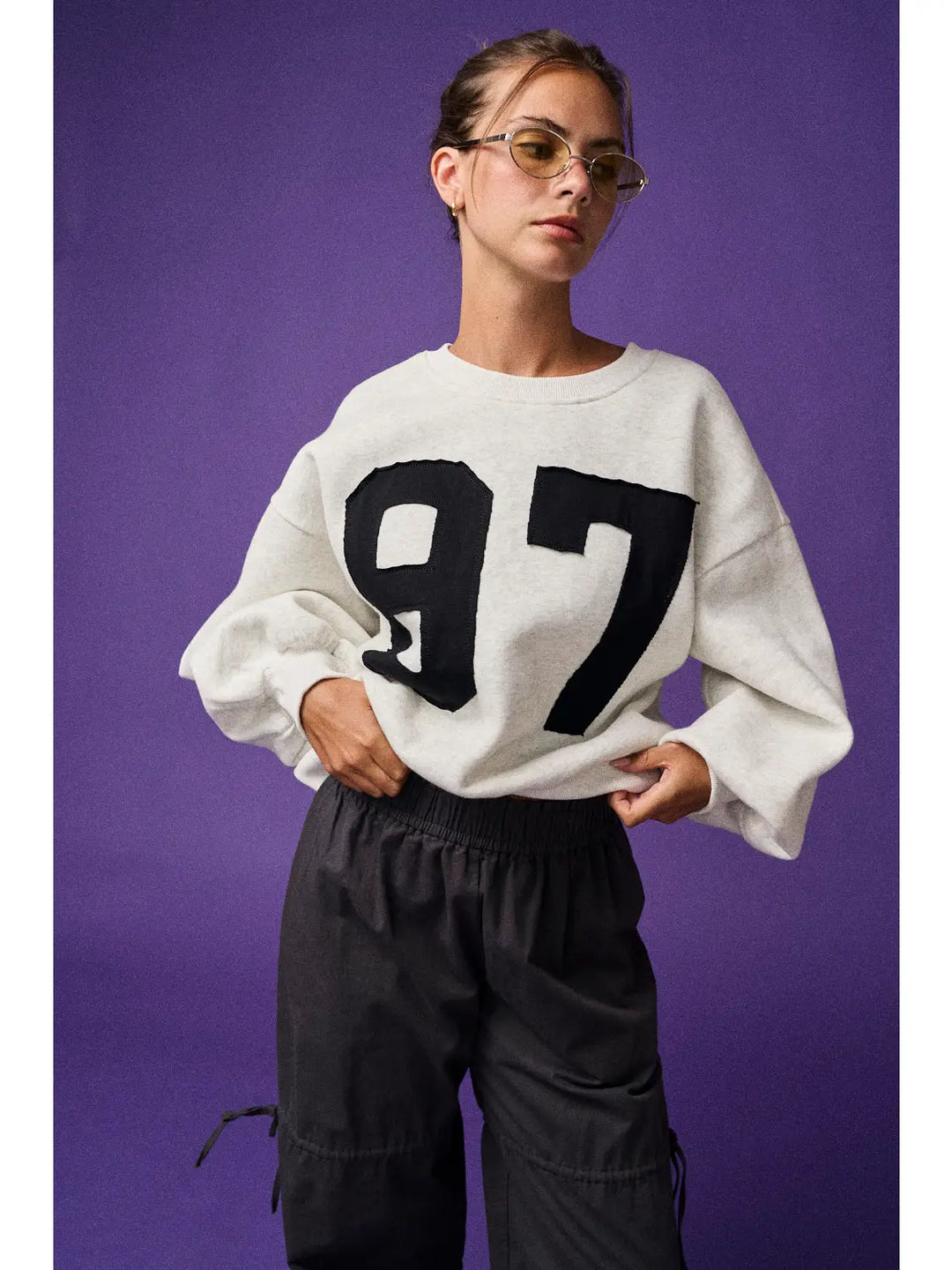 Person wearing a white sweater with black numbers on a purple background