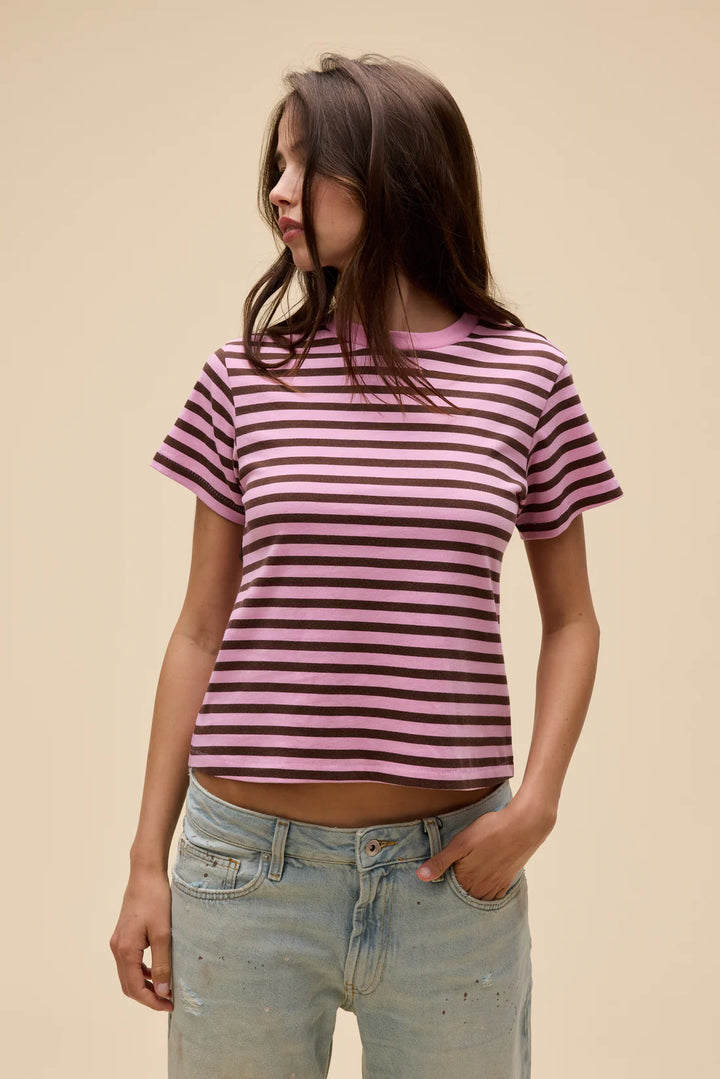 Person wearing a pink and purple striped t-shirt with light blue jeans on a beige background