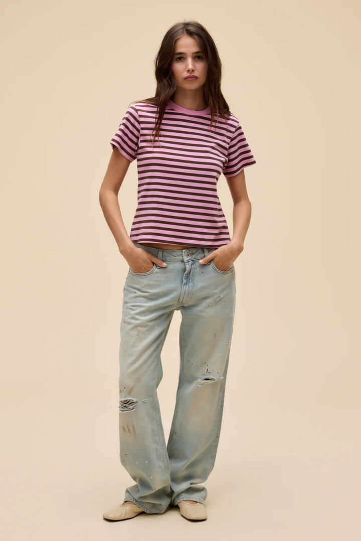 Woman wearing a striped shirt and light blue jeans against a beige background