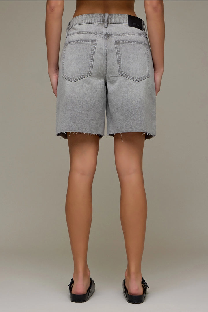 Person wearing gray denim shorts on a plain background
