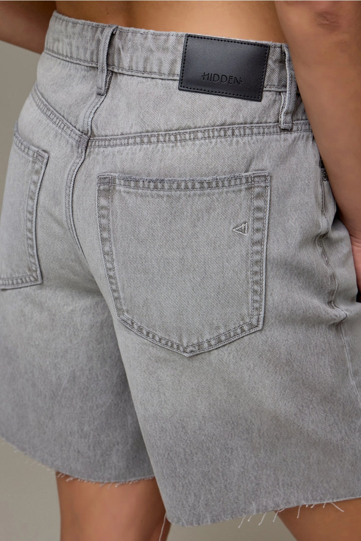 Gray denim shorts with a brand label on a neutral background