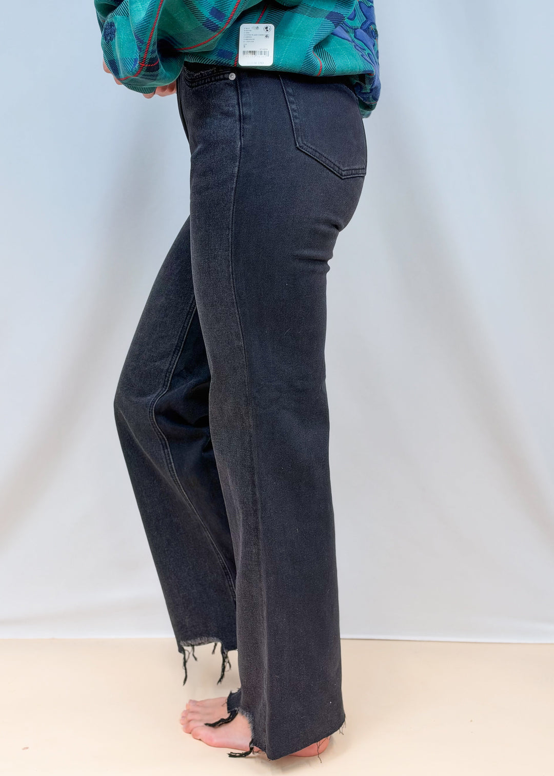 Woman shown from side view waist down wearing black flare denim jeans on plain background