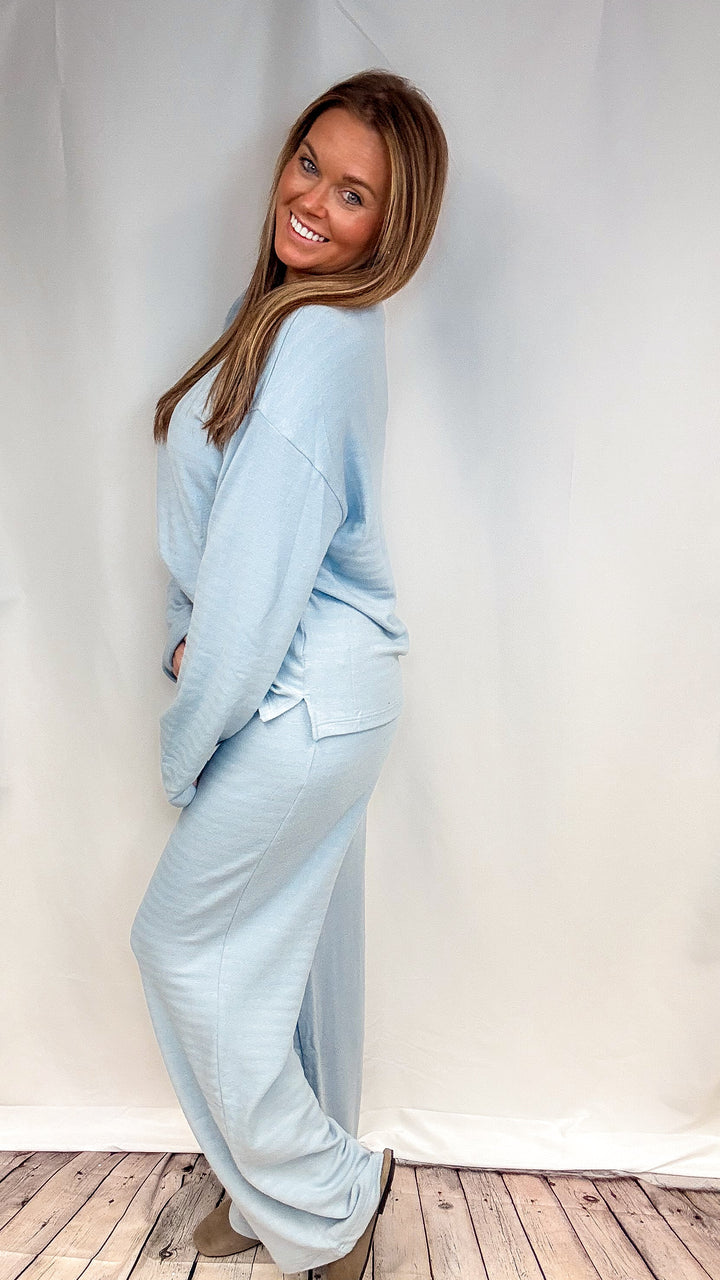Woman wearing matching light blue knit set on plain background
