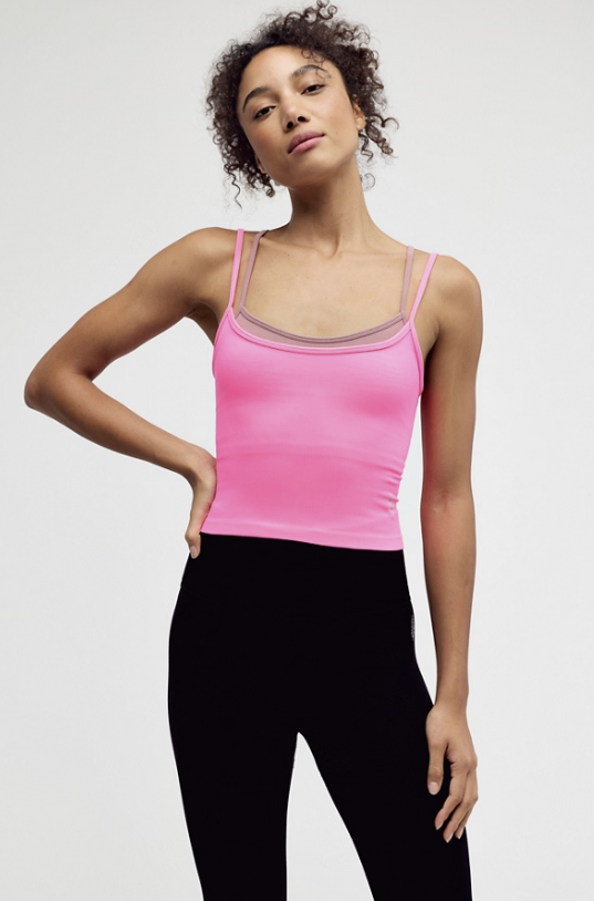 woman wearing hot pink tank and black leggings on white background