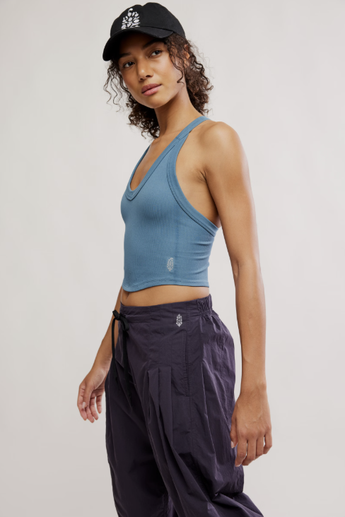 woman wearing blue tank top and purple pants on plain background