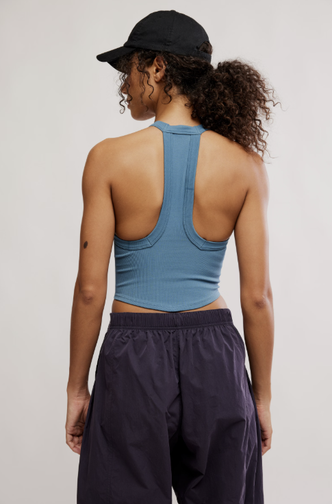 Person wearing a blue sports bra and black cap on a plain background