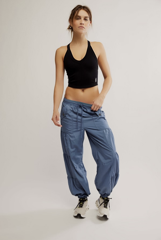 Woman wearing a black sports bra and blue pants on a white background