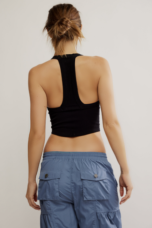 Person wearing a black crop top and blue cargo pants on a plain background
