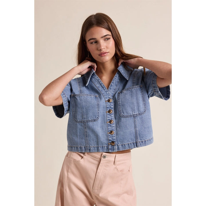 woman wearing denim top on plain background