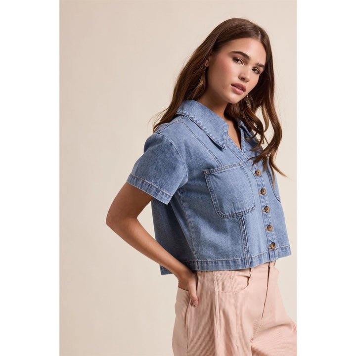 woman wearing denim top on plain background