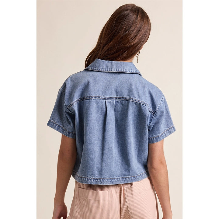 woman wearing denim top on plain background