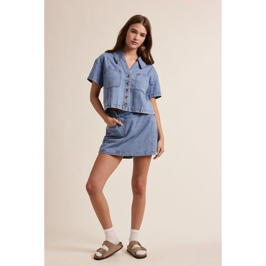woman wearing denim top and skort on plain background