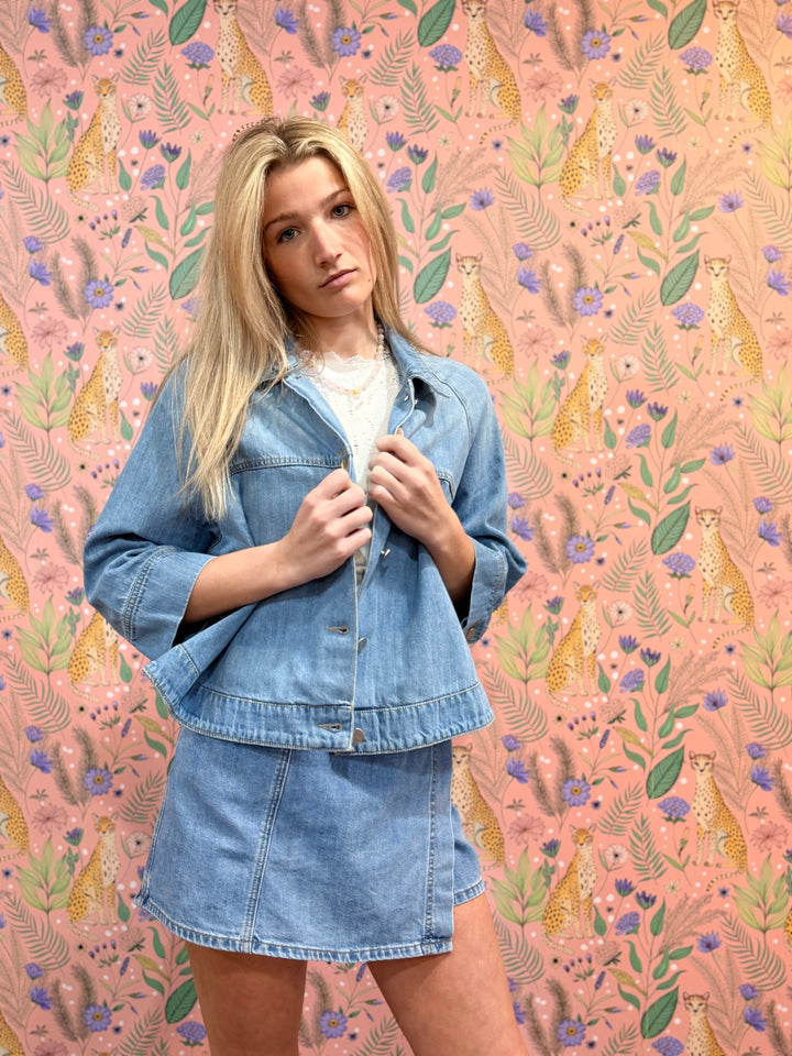 Woman in denim outfit standing against a patterned background
