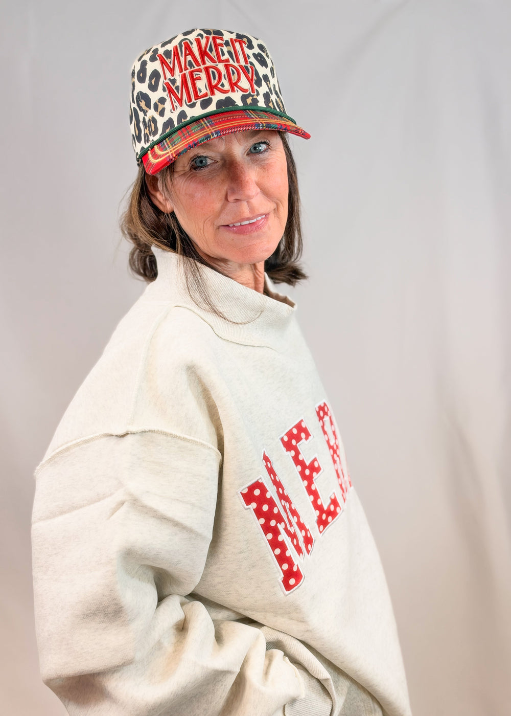 Woman wearing grey mock neck sweatshirt on plain background