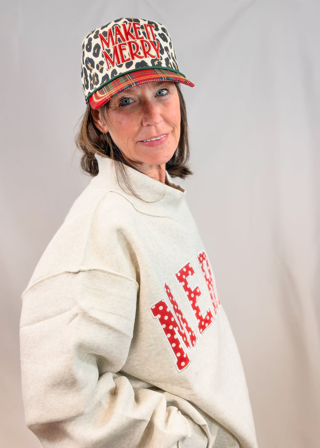 Woman wearing grey mock neck sweatshirt on plain background