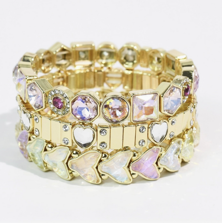 Three gold stretch bracelets with gemstones stacked on white background