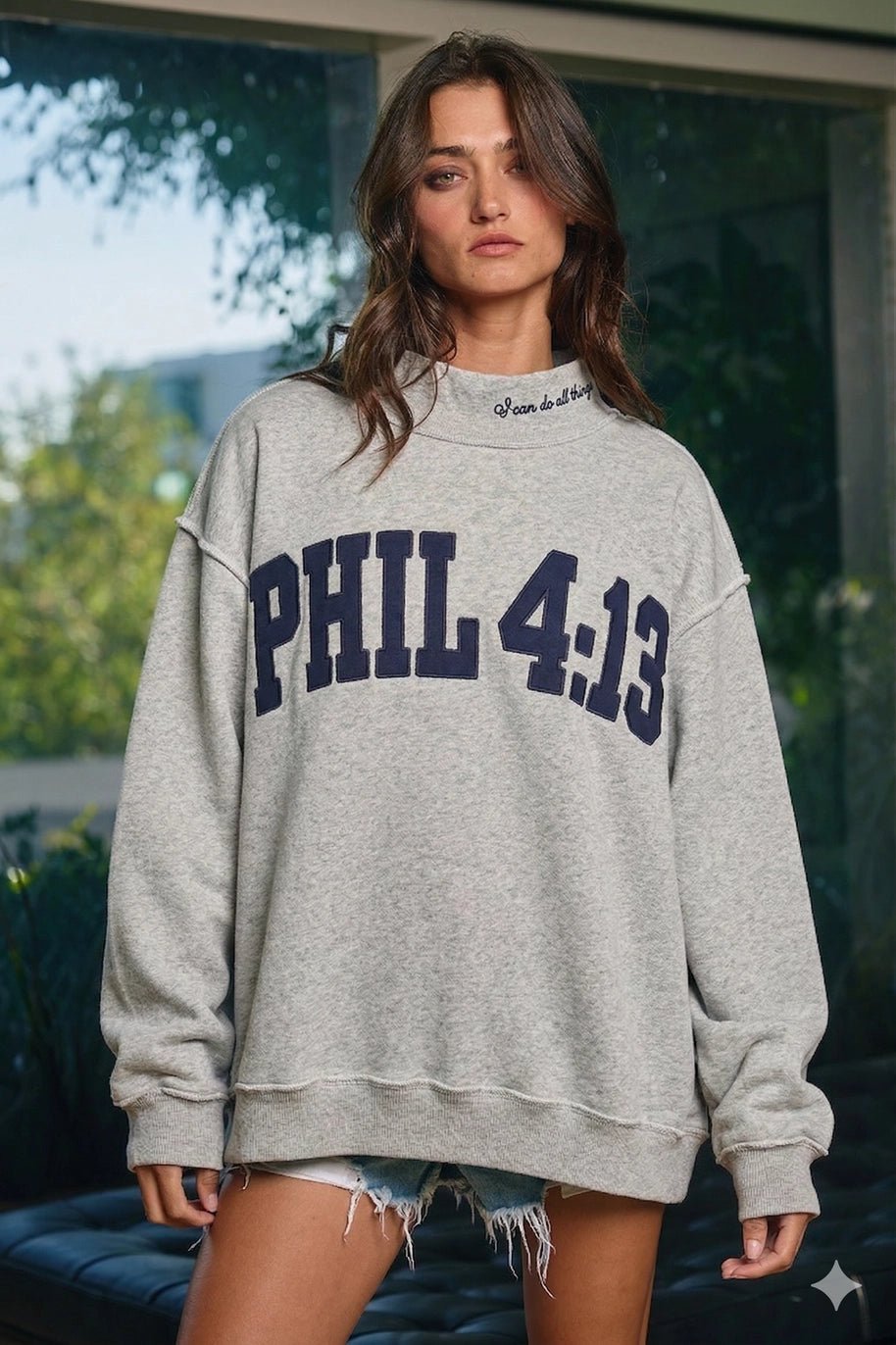 Woman wearing a gray sweatshirt with 'PHIL 4:13' text outdoors.