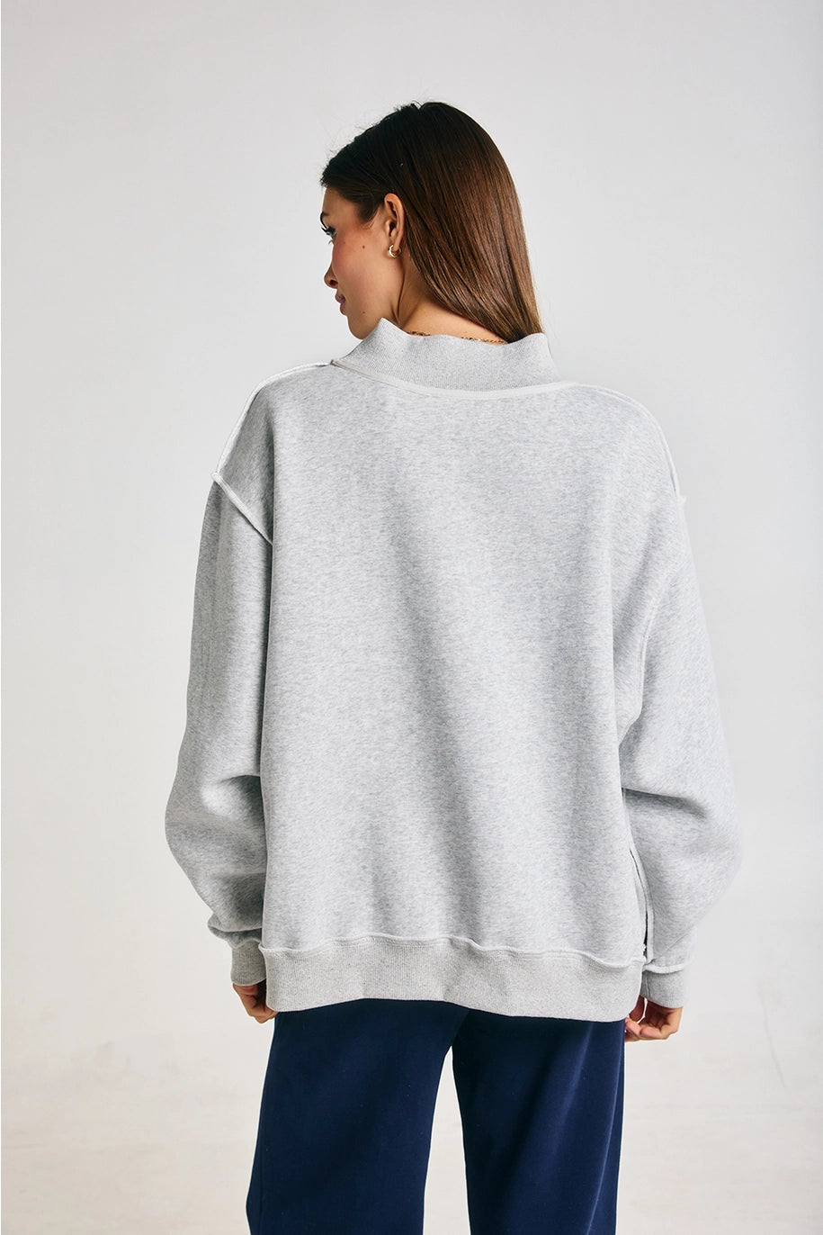 Person wearing a gray sweatshirt and blue pants on a white background