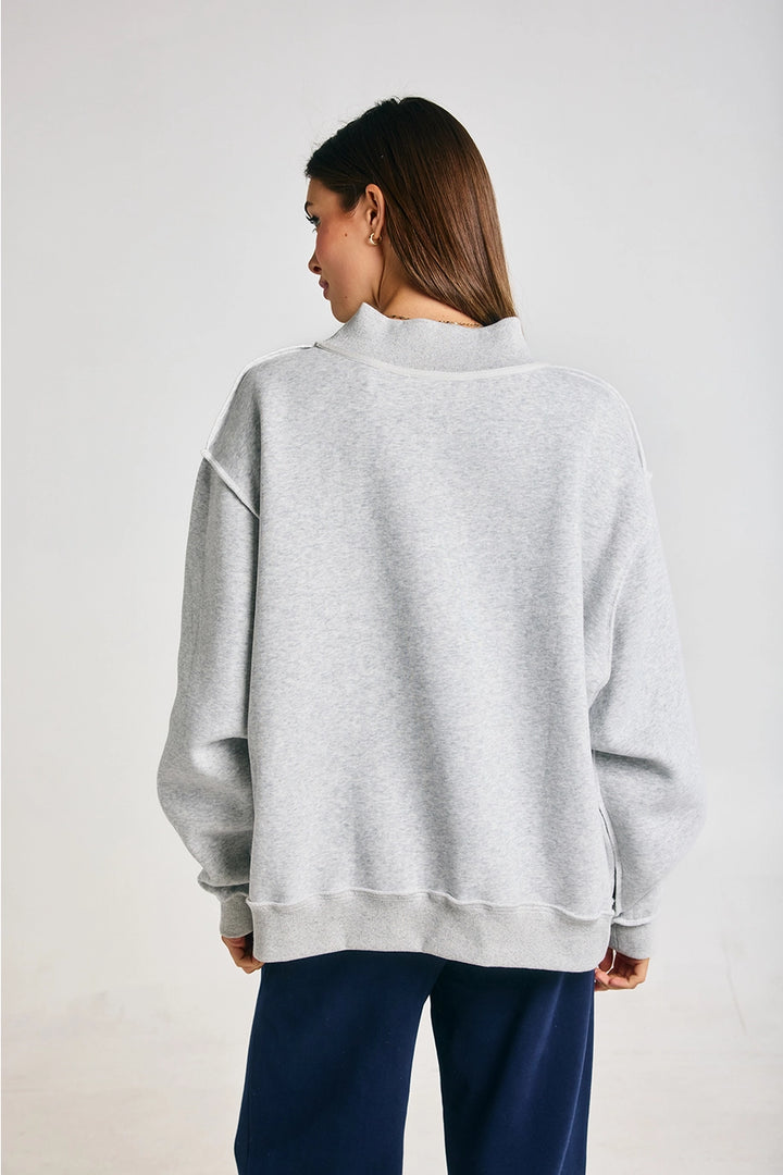 Person wearing a gray sweatshirt and blue pants on a white background