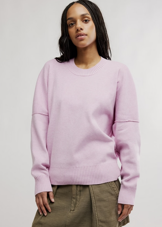 Woman wearing light purple pullover with olive skirt on plain background