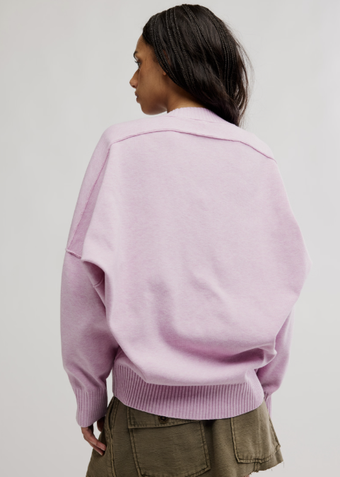 Woman shown from back wearing light purple pullover and olive skirt on plain background