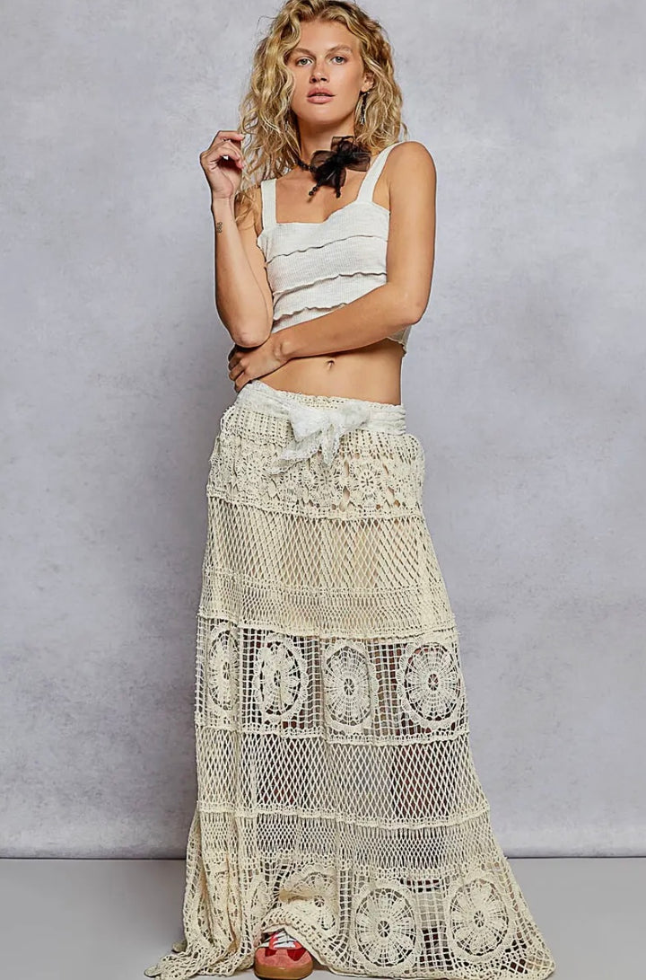 Woman wearing a white lace skirt and top against a gray background
