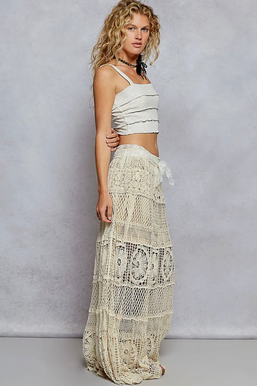 Woman wearing a white lace skirt and top against a plain background