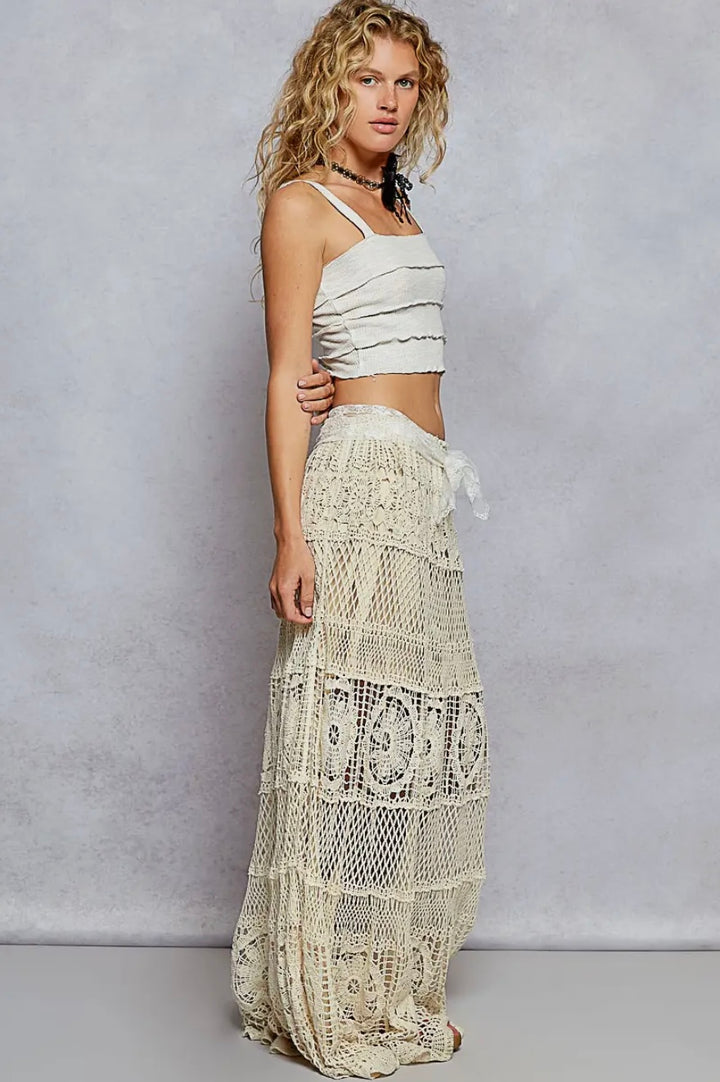 Woman wearing a white lace skirt and top against a plain background