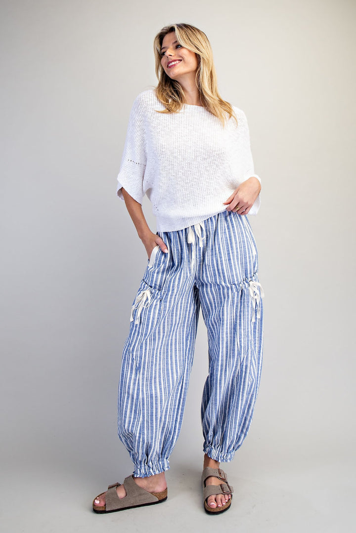 Woman wearing blue stripe pants and white shirt on plain background