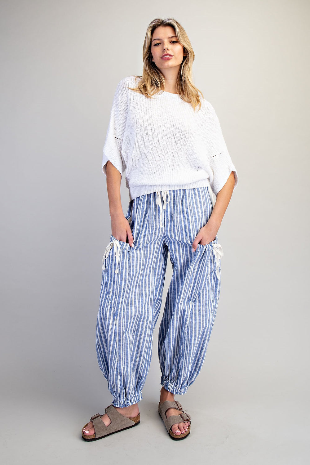 Woman wearing blue stripe pants and white shirt on plain background