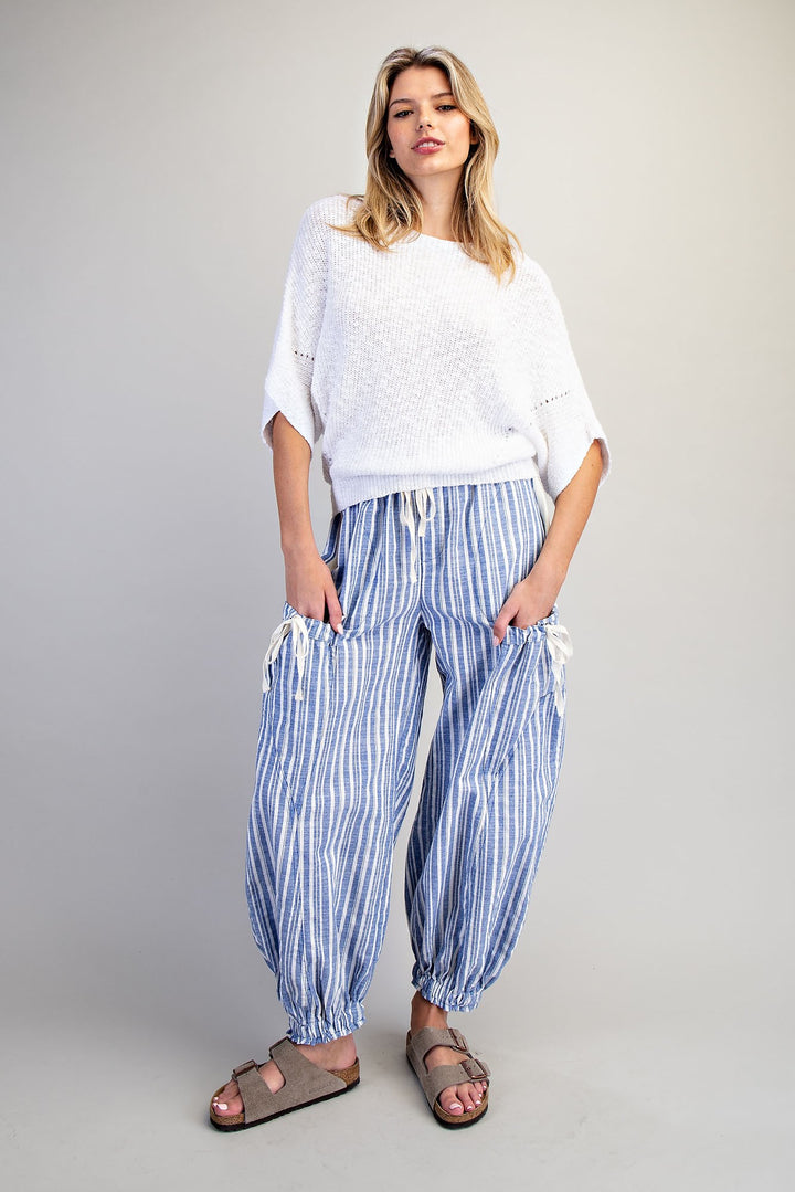 Woman wearing blue stripe pants and white shirt on plain background