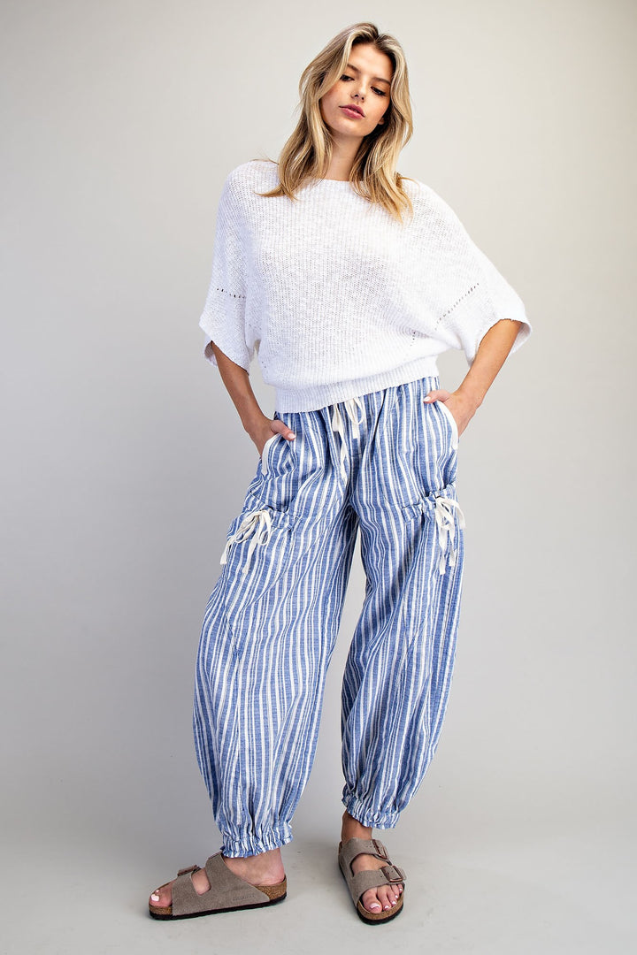 Woman wearing blue stripe pants and white shirt on plain background