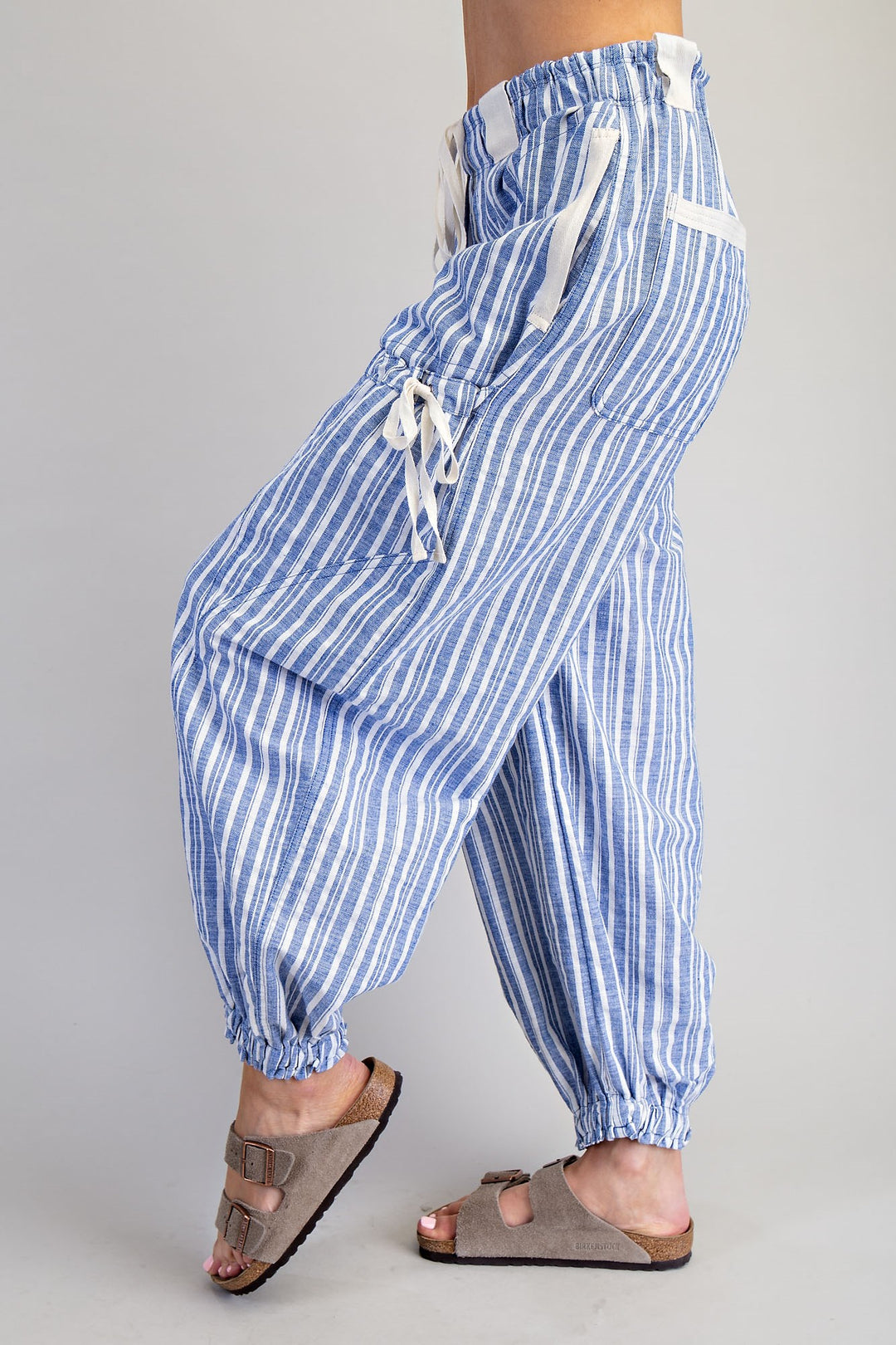 Woman wearing blue stipe pants on plain background