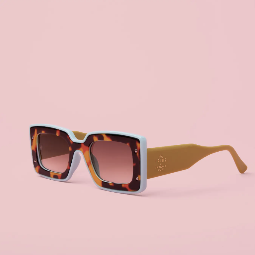 Square sunglasses with a light blue and tortoiseshell acetate frame, brown gradient lenses, and tan temples, shown on a solid pink background.