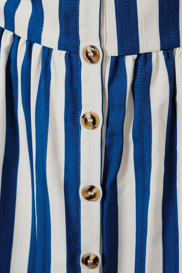 Close-up of a blue and white striped dress with gold buttons.