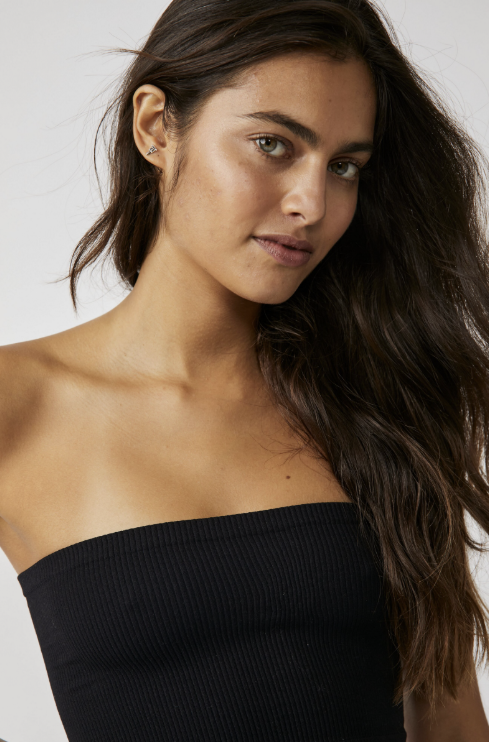 Woman wearing a black strapless top against a plain background