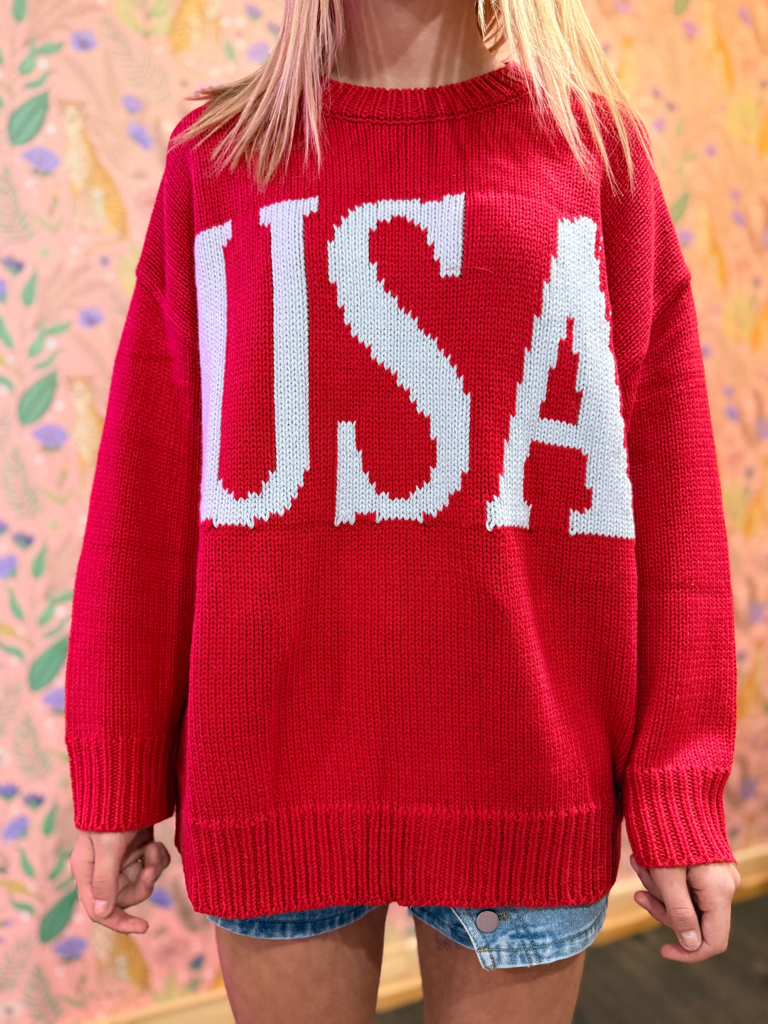 Woman wearing red sweater with "USA" writing on blurred background