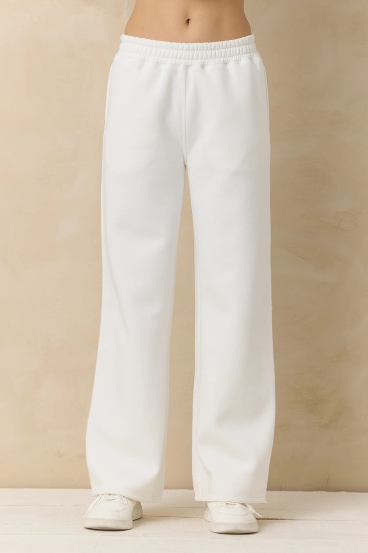 White sweatpants worn by a person on a beige background