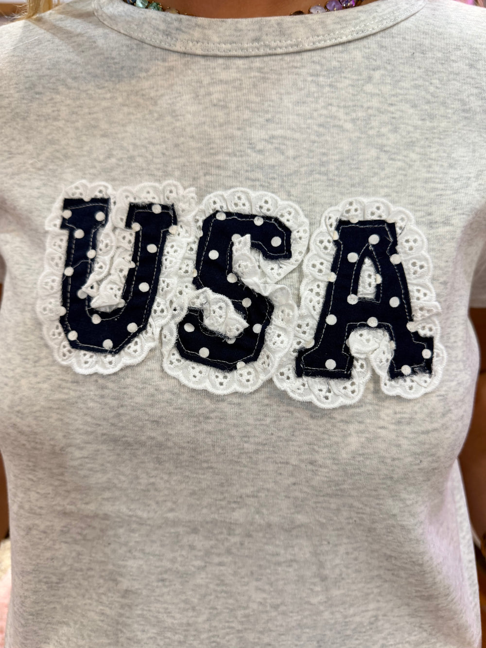 Gray t-shirt with 'USA' text in black and white lace on a plain background