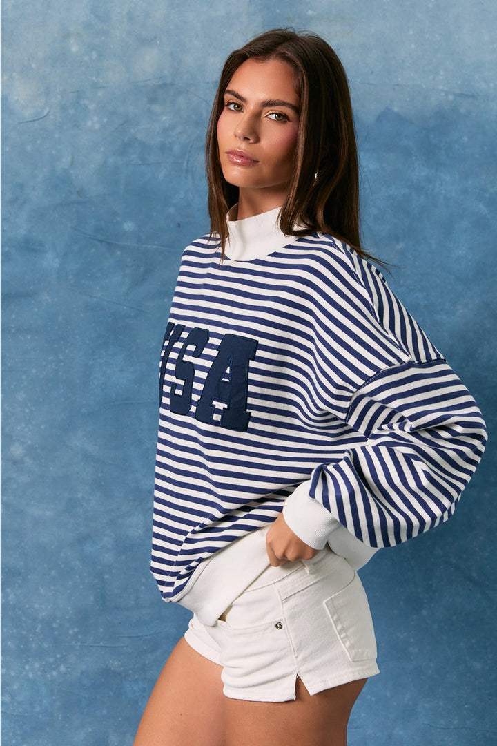 Woman wearing a blue and white striped sweater with &
