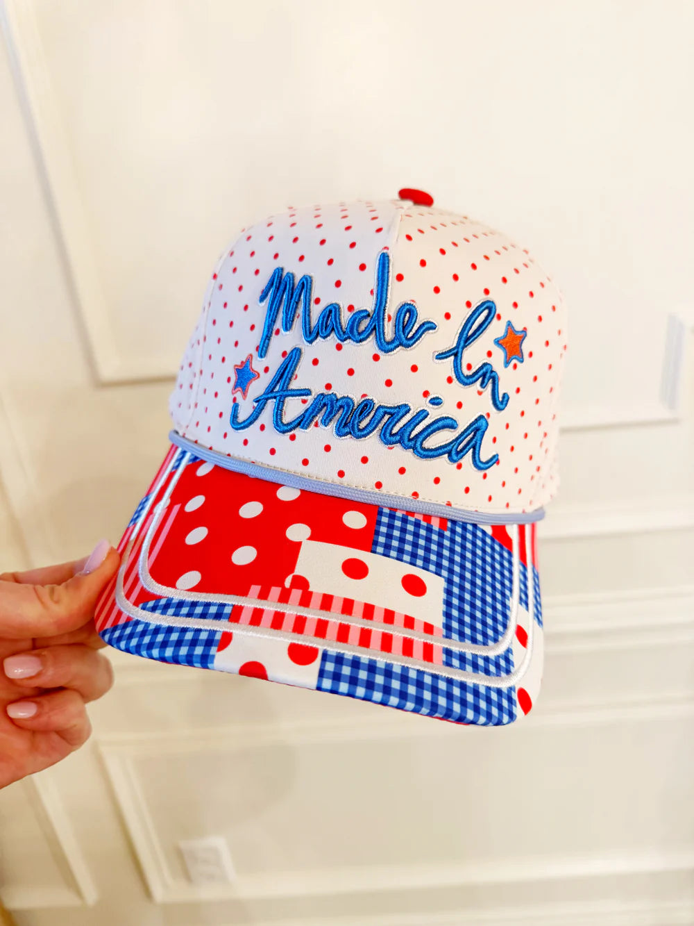 Cap with 'Made in America' text and polka dot pattern held by a hand against a white background