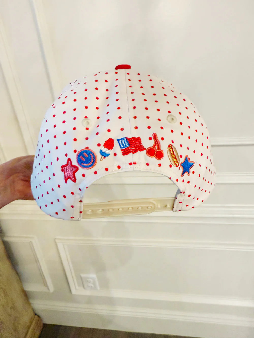 Polka dot cap with colorful designs on a white wall