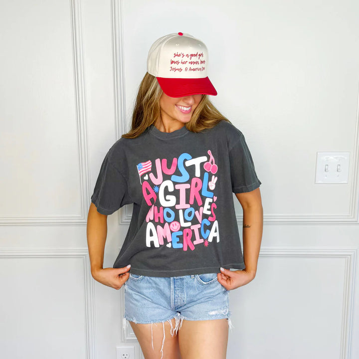 Woman wearing black graphic tee and jean shorts on white background