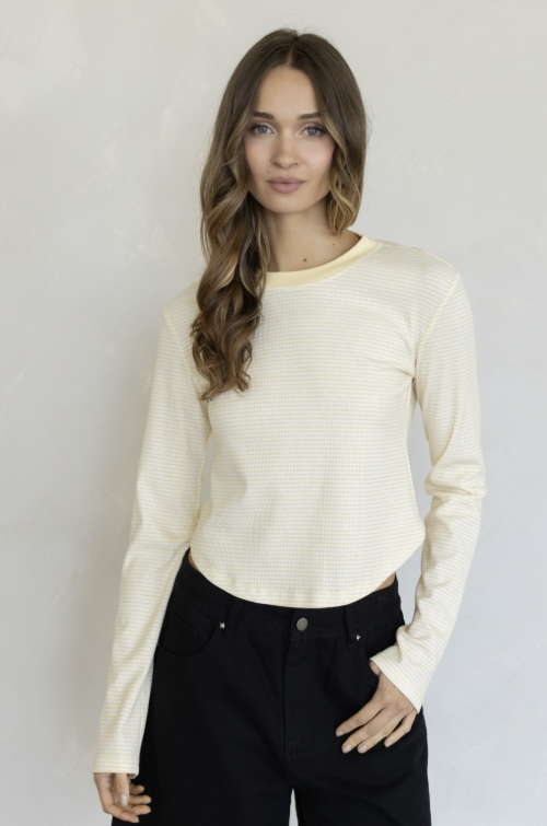 Woman wearing yellow stripe shirt and black pants on plain background