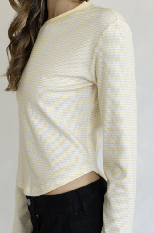 Woman wearing yellow stripe long sleeve shirt and black pants on plain background