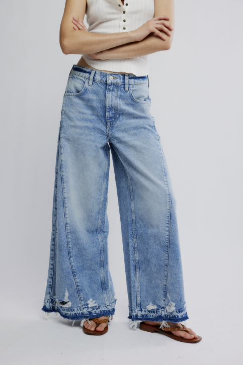 Person wearing light blue wide-leg jeans on a plain background