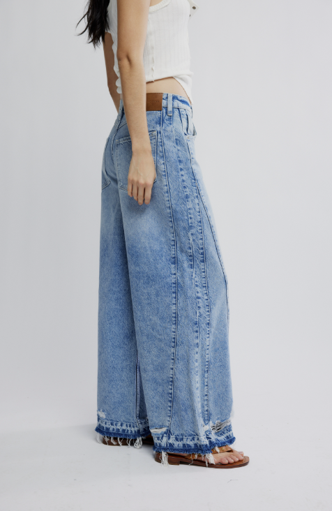 Person wearing wide-leg blue jeans on a plain background